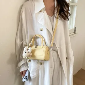 Stylish yellow mini barrel bag with cute dog pendant, versatile crossbody design for women.