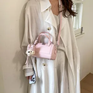 Chic pink leather shoulder pillow bag with cute puppy pendant, stylish crossbody design.
