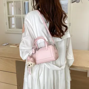 Detail view of pink leather pillow bag with cute plush bear pendant, stylish crossbody purse.