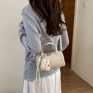 Detail shot of chic beige pillow shoulder bag with cute plush charm, versatile daily commuting use.