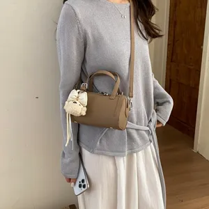 Chic brown cylindrical pillow shoulder bag with cute plush pendant for women stylish daily