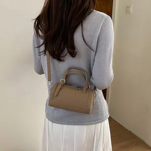 Detail shot of stylish brown cylindrical crossbody pillow bag worn by model, chic daily accessory.