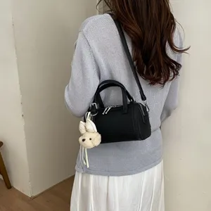 Detailed view of the chic black leather pillow bag with cute puppy charm and shoulder strap.
