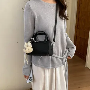Classic black cylindrical shoulder bag with cute plush charm, perfect for daily commute and styling.