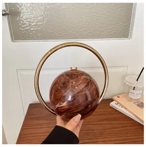 Detailed view of unique sphere resin handbag with golden round handle for evening and commute style.