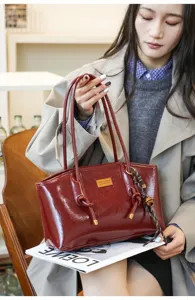 Detailed shot of dark red patent leather tote bag, casual commuter shoulder bag style.