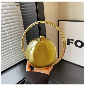 Golden metallic ball handbag detail, circular ring handle, elegant evening party accessory.