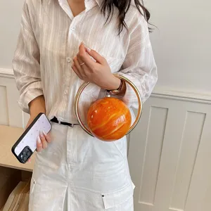Exquisite round evening handbag detail showing unique orange marble texture and chic gold ring handle.
