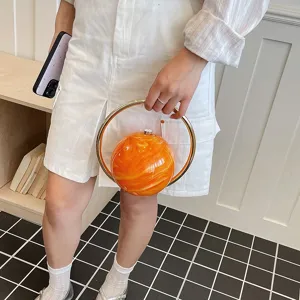 Detail view of the orange marble spherical clutch bag with elegant gold metal ring handle.