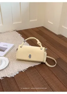 Λεπτομερής εικόνα κομψής ανοιχτής κίτρινης δερμάτινης τσάντας χειρός με μεταλλικό κούμπωμα.