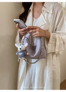Detailansicht der modischen Lederhobo-Dumpling-Tasche mit Kette und süßem Plüsch-Anhänger.