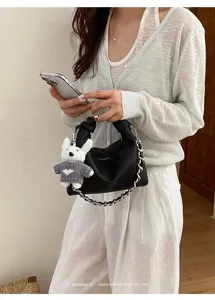 Schwarze Leder Hobo Tasche mit Metall Kette und süßem Bärenanhänger, schöne Detailansicht.
