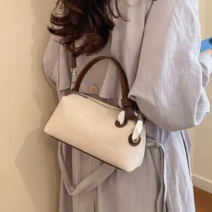 Gros plan d'un sac à épaule texturé élégant avec poignée en cuir marron et détails en métal chic.