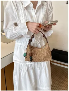 Detailansicht der geflochtenen Strohtasche mit bunten Perlen und braunem Ledergriff.