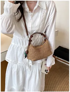 Detailansicht einer sommerlichen Strohgewebten Tasche mit braunem Lederriemen und bunten Perlen.