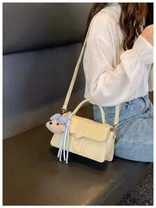 Detailansicht der stilvollen beige Umhängetasche mit süßem Bärenanhänger und Ledergurt.