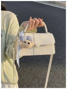Stilvolles beiges Umhängetasche Detail mit süßem Plüsch Hund Anhänger und eleganter Griff.