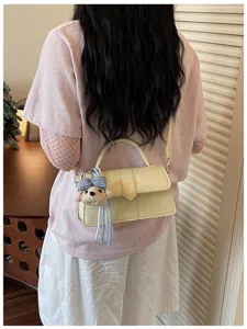 Detailansicht der modischen Damen Umhängetasche und Handtasche mit süßem Bärenanhänger.