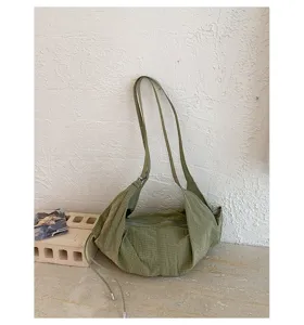 Green plaid canvas shoulder bag detail showing textured fabric and slouchy design for casual daily use.