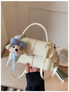 Schicke beige Umhängetasche Detail mit süßem Plüschwelpen Anhänger und elegantem Schnallenriemen.