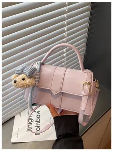 Lila PU-Leder Umhängetasche Detailansicht mit süßem Plüschbär Anhänger und Riemen.