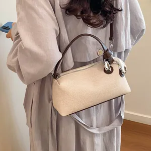 Vue détaillée d'un sac oreiller d'épaule beige élégant avec poignées marron et anneau argenté.