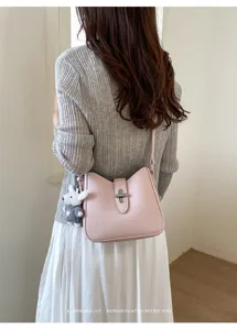 Schicke rosa Leder Umhängetasche mit Metallverschluss und Plüsch Anhänger für Damen.