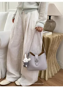Detailansicht der minimalen lila Umhängetasche mit Hasenanhänger, elegante lässige Alltagskleidung.