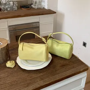 Vista detallada de un bolso de hombro cilíndrico verde pálido de moda con cremallera y asa.