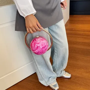 Detail view of the unique round marble pattern handbag featuring sleek metallic ring handles.