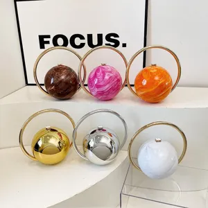 Stylish round sphere evening handbag with metal ring handle, chic marble and metallic design.