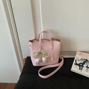 Rosa Leder Eimer Tasche Detailaufnahme mit feiner Textur und edlem Perlen Tulpen Anhänger.