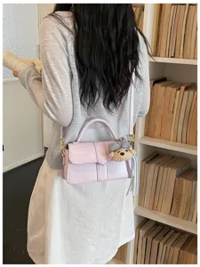 Detailaufnahme der stilvollen rosa Schultertasche mit süßem Bärenanhänger im Regal.
