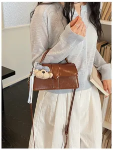 Detailansicht der braunen Handtasche aus Lackleder mit süßem Plüschbären Anhänger Szene
