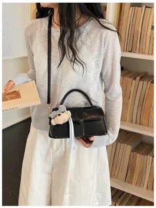 Schwarze glänzende Umhängetasche für Damen, schicke quadratische Tasche mit Bärenanhänger.