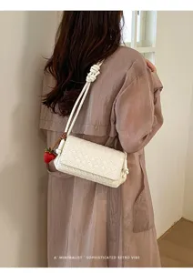 Stylish white woven shoulder bag for women, minimalist underarm handbag with charm.