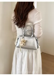 Metallische silberne Boston Handtasche mit Bärenanhänger, stilvolles Design für Alltag.