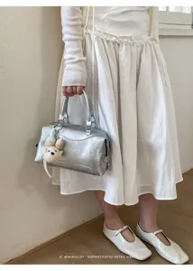 Nahaufnahme einer stilvollen silbernen Boston Handtasche mit süßem Plüsch-Anhänger, absolut chic.
