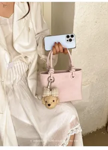 Nahaufnahme der rosa Handtasche mit süßem Bären-Plüsch-Anhänger und knoten Griff Design.