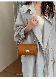 Primo piano della borsa a spalla marrone con elegante catena in metallo e chiusura.