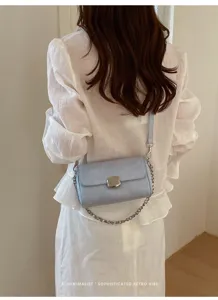 Dettaglio borsa a tracolla retro minimalista, elegante borsetta con catena azzurra.