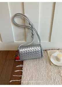 Silver woven leather shoulder bag with knotted strap and cute charm for women everyday use.
