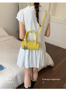 Yellow cylindrical crossbody bag with star charm, showing detailed rear view on model.