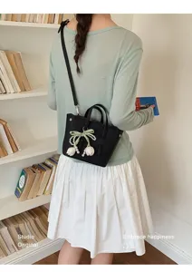 Elegante schwarze Damentasche als Eimertasche mit Perlen und Schleife, schicke Umhängetasche.