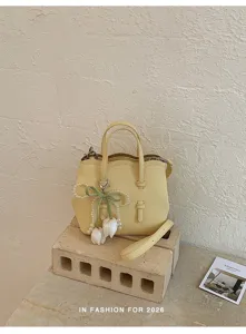 Detailaufnahme der gelben Handtasche aus Kunstleder mit süßem Perlen-Tulpen-Anhänger.
