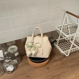 Nahaufnahme Detail des beigen Eimerbeutels mit elegantem Perlen Tulpen Anhänger Griff.