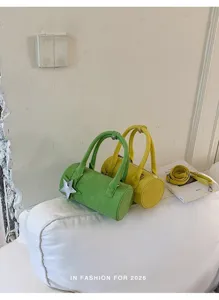Cylinder handbag detail shot, green and yellow colors, metal zipper, cute star pendant.