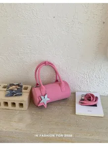 Pink cylindrical shoulder bag detail, stylish barrel design with cute star pendant charm.