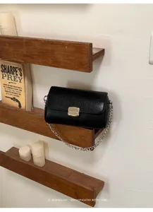Borsa a tracolla quadrata nera da donna con elegante catena argentata e chiusura in metallo.