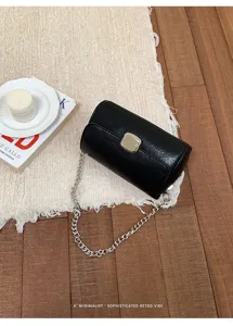 Elegante borsa a tracolla cilindrica nera con catena argentata e chiusura da donna.
